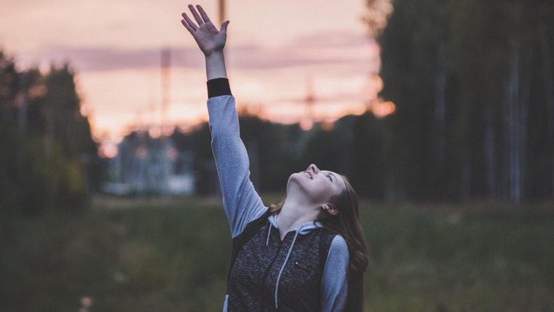 girl looking straight up lifting hand upward