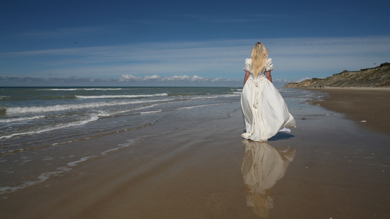 lone bride walking on beach