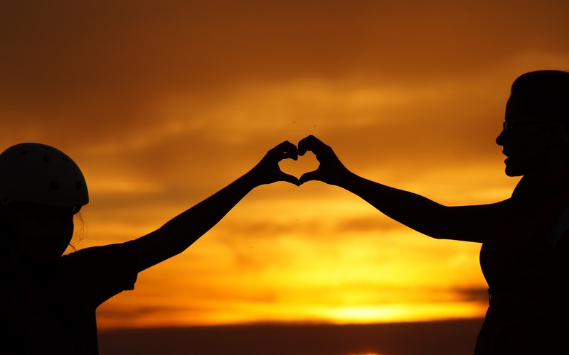 two girls making heart symbol by joining hands