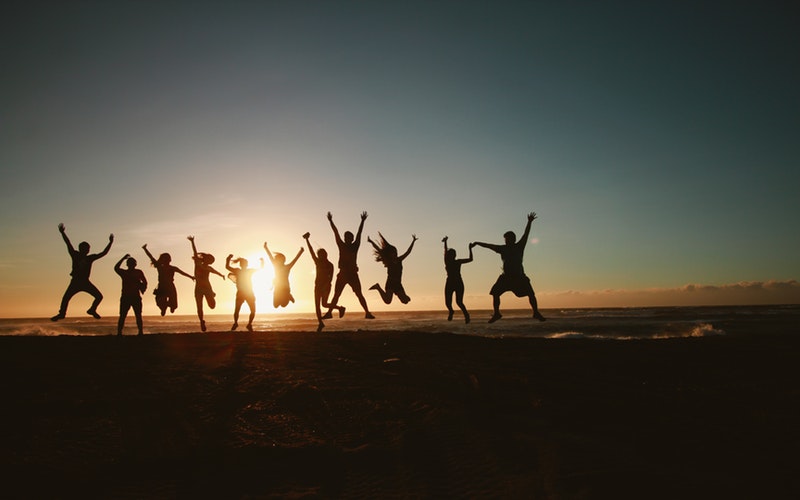 row of silhouetted people jumping in air