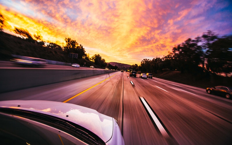 speed warp car on interstate into sunset