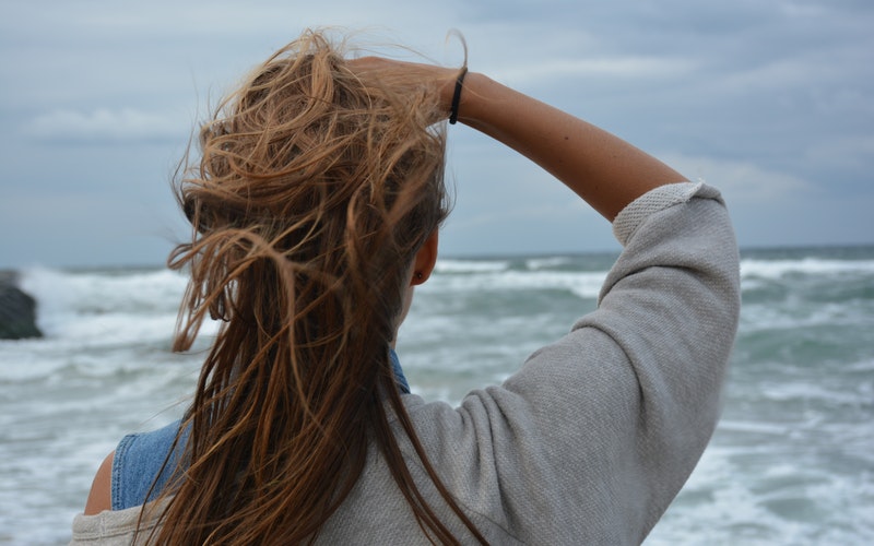 back of woman who is facing ocean