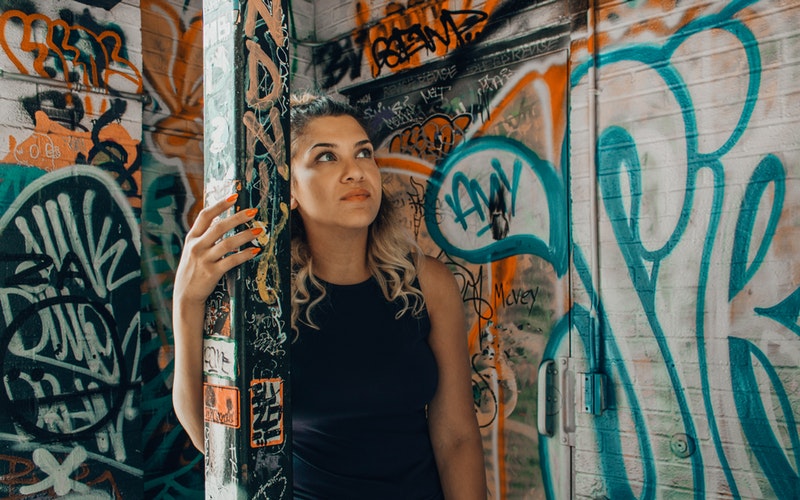 woman standing in graffiti filled corner