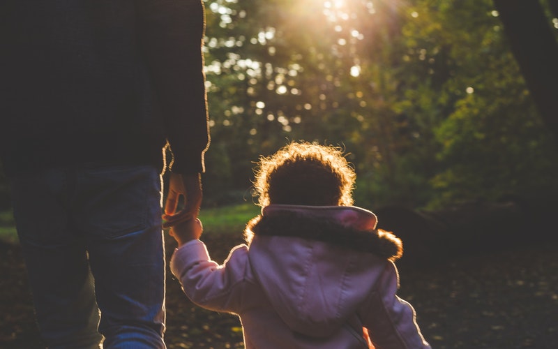 toddler holding the hand of her father