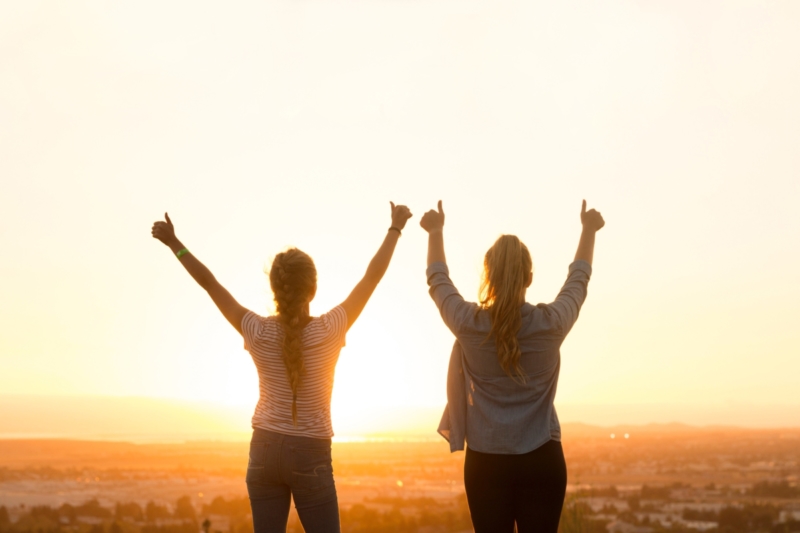 two women hands in the air thumbs up