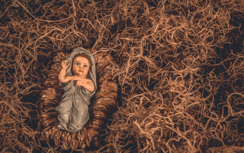 vintage baby Jesus figurine in manager displayed in moss