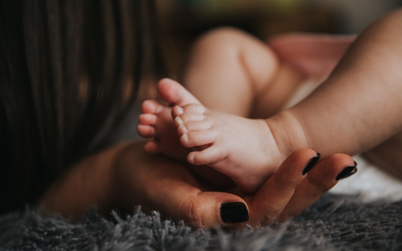 female hand cradling tiny baby feet