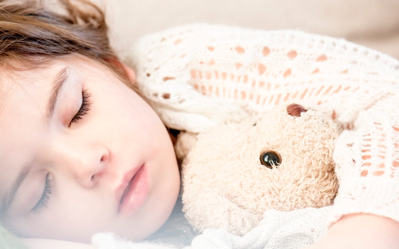 a female child sleeping clutching teddy bear