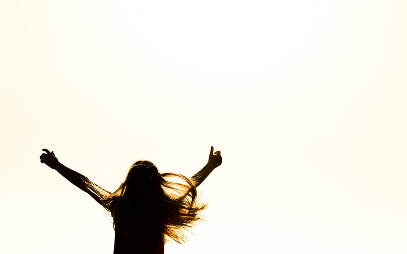 white background, silhouette of long haired girl hands raised in the air like she's dancing