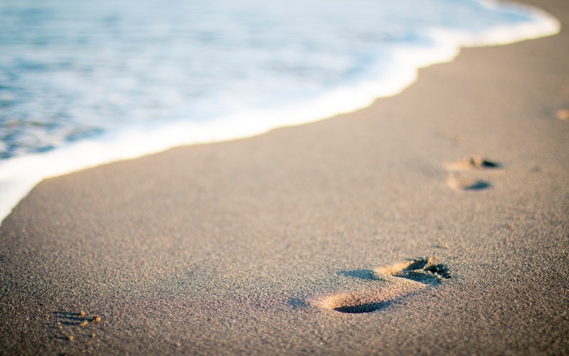 The Beloved, shoreline, white foam rolling up on beach, footprints in the sand