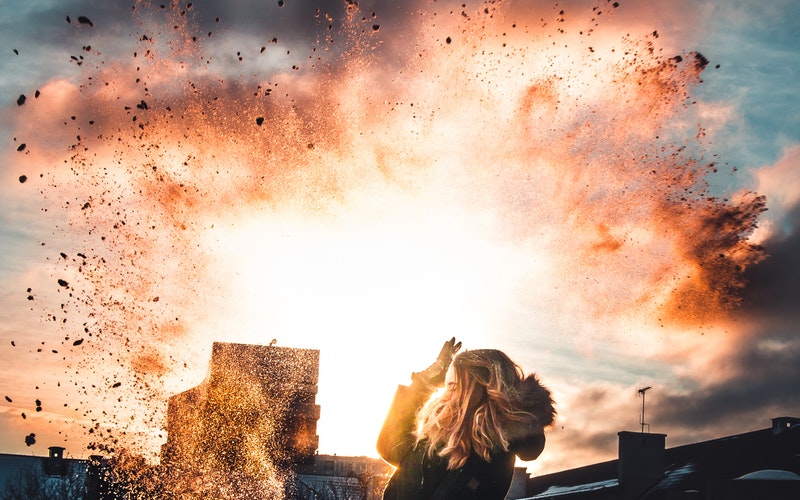 blond girl with coat and gloves, throwing dirt into the air