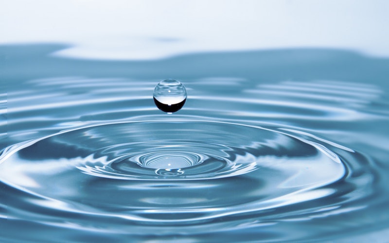 Good Virus, image is close up of a drop of water falling into the water below causing a ripple