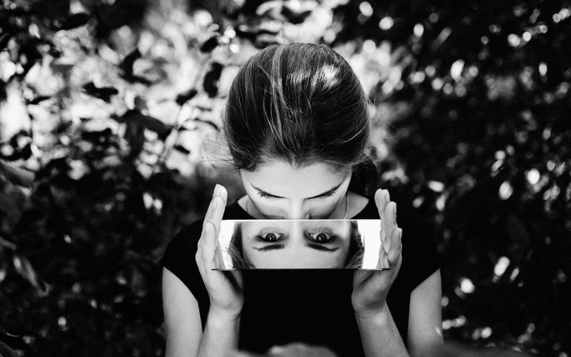 black and white image of woman looking down into a mirror for the Heart post