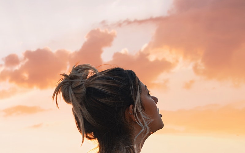 Recovery, woman looking skyward into a pastel sky, clouds