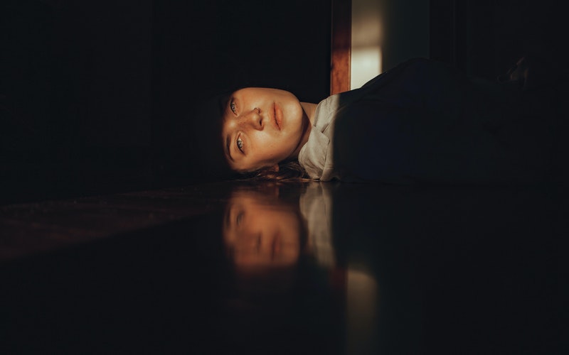 girl on floor in the dark with a ray of light across her face - Holy Moments