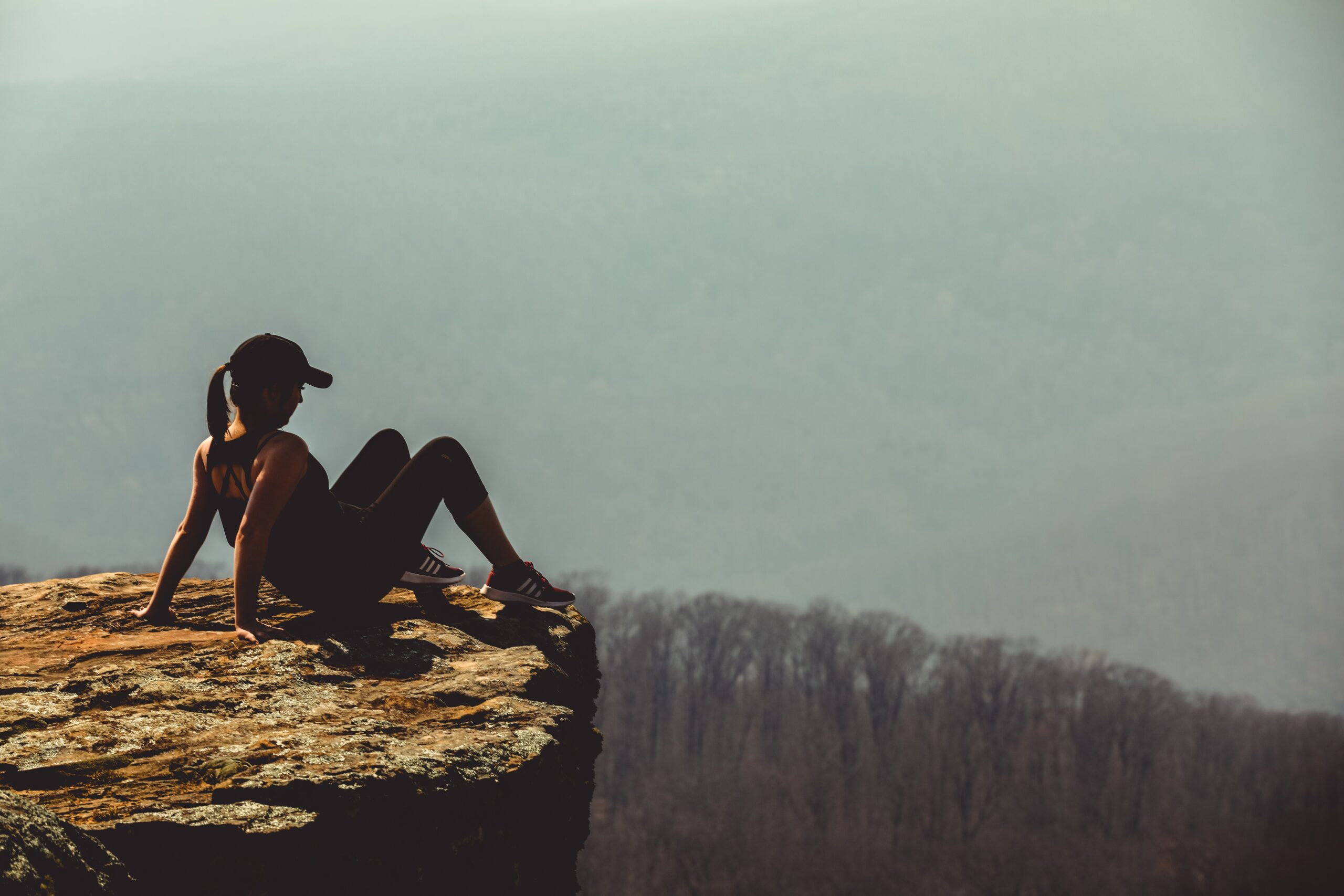 woman sitting on edge of a cliff looking off into the distance Dear God