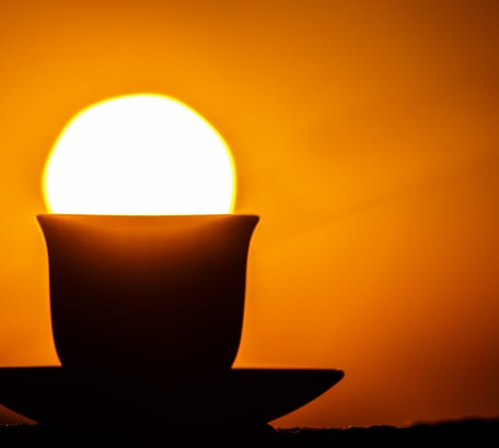 coffee cup on saucer positioned right under the setting sun 3 reasons to read your bible