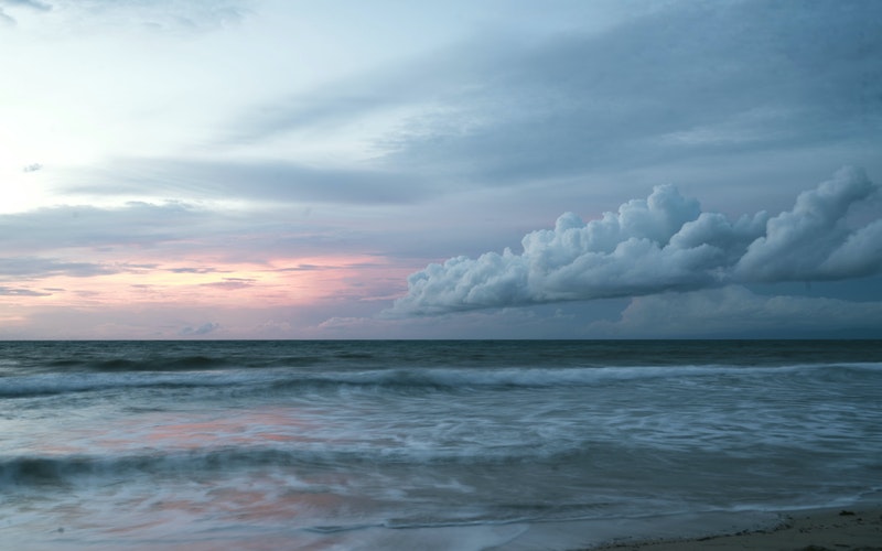 muted landscape of the ocean and sky, part of the sky has the sunsetting and the other is dark clouds forming, blog post God's Table