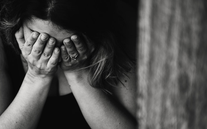 black and white image of a woman crying with head in hands. Orphaned Hearts