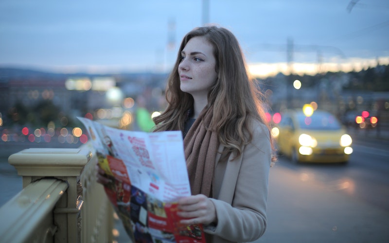 Young woman standing in a busy street with a city map. there's a better way.