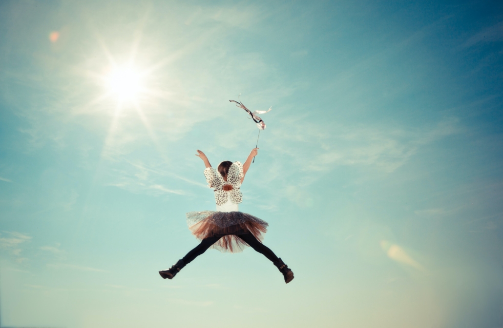 girl in tights, tutu and holding wand over her head jumping high in the air, new beginnings