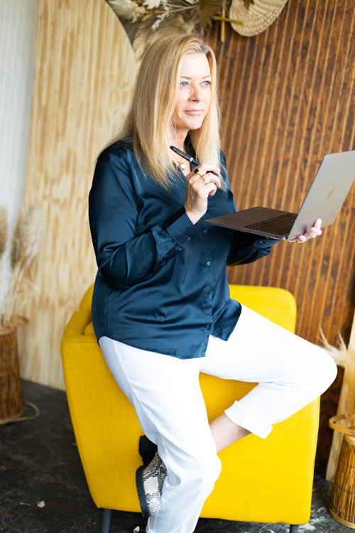 Sherrie sittin gon the back of a chair with her computer