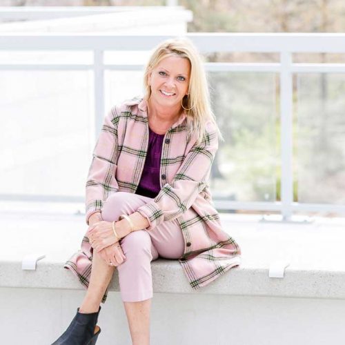 Sherrie smiling, sitting on a deck overlooking a park
